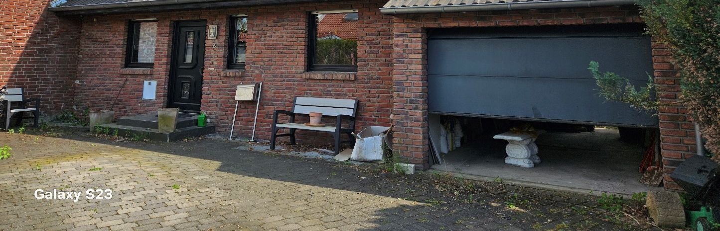 Vorderansicht eines Backsteinhauses mit Eingangstür, Fenstern, Garage und gepflastertem Vorplatz in Holzwickede