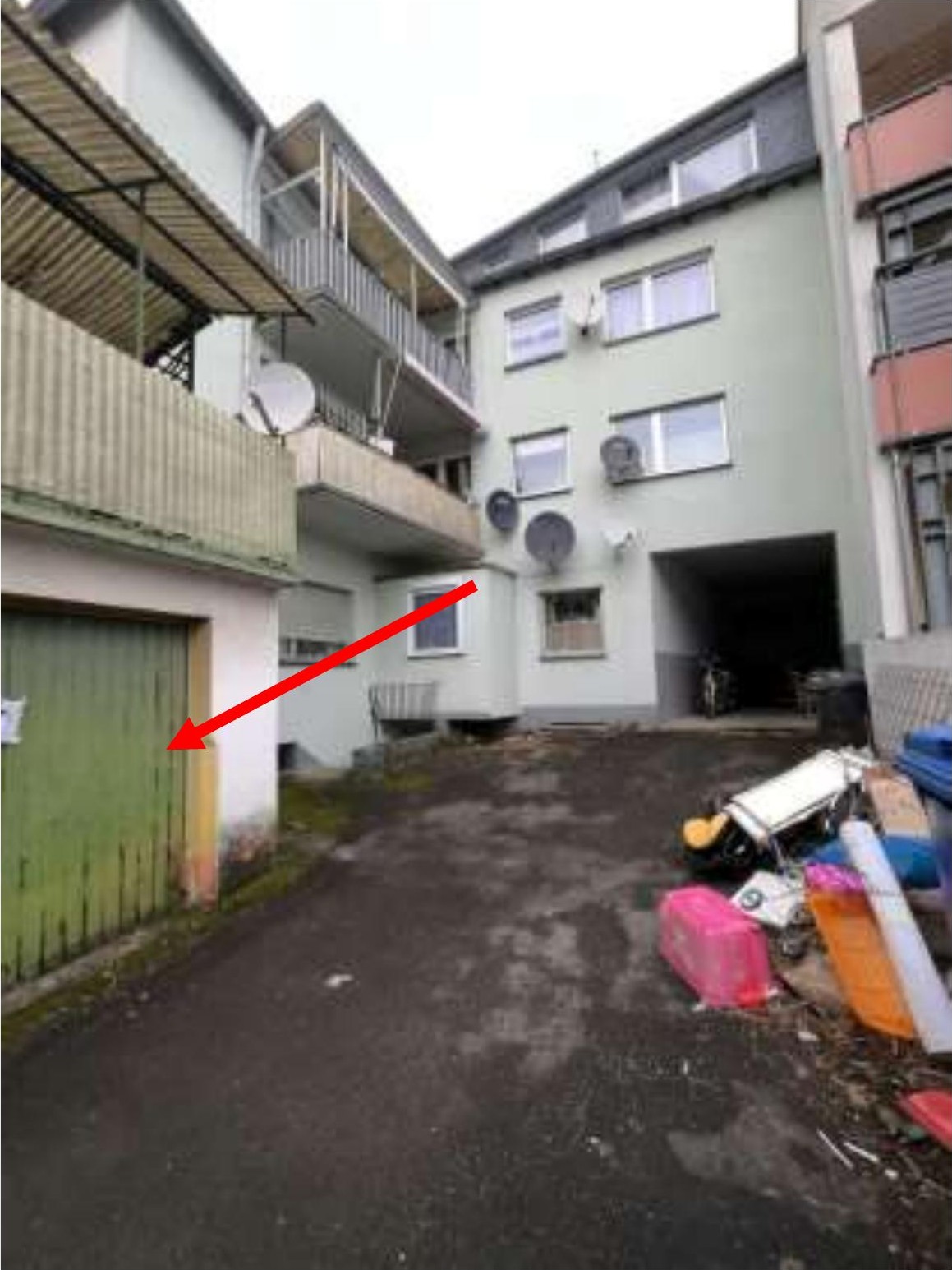 Hinterhof mit grüner Garagentür, umgeben von Wohngebäuden mit Balkonen und Satellitenschüsseln, Köln, Blumenthalstraße 23