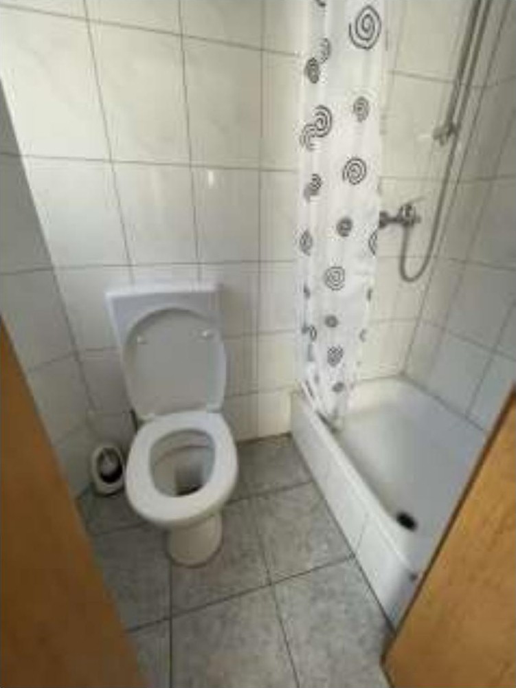 Badezimmer mit Toilette, Dusche und Fliesenwand, Teil eines Wohn-/Geschäftshauses in Duisburg