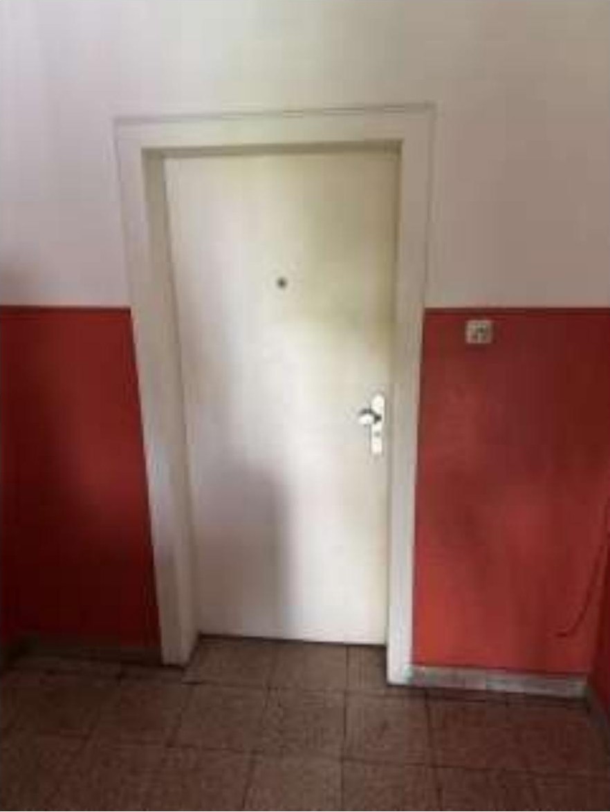 Innenraum mit weißer Tür, rotem und weißem Wandverputz sowie gefliestem Boden in einer Eigentumswohnung in Duisburg