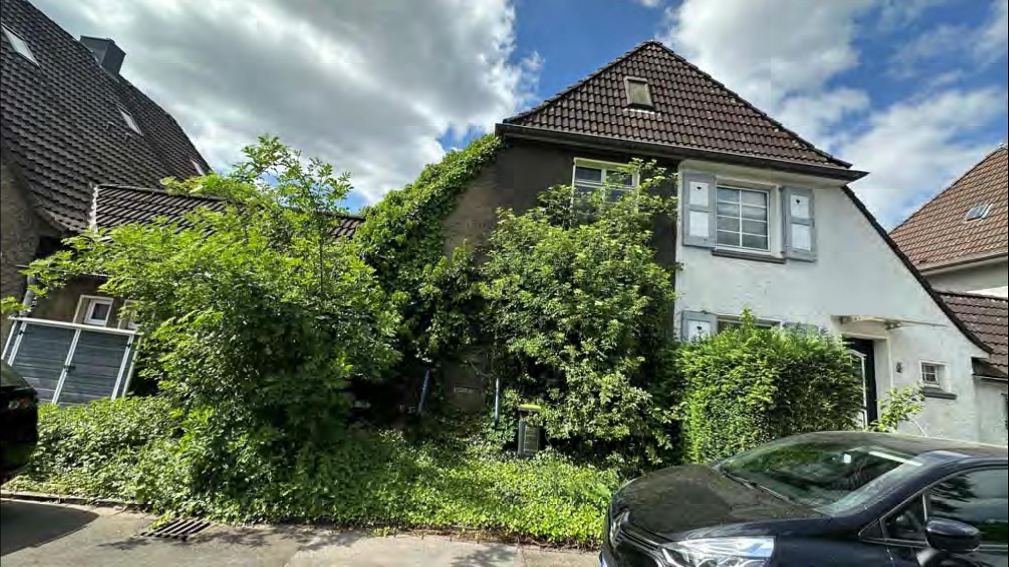 Vorderansicht eines Einfamilienhauses mit Satteldach, teilweise bewachsenen Wänden und Vorgarten in Duisburg, Franz-Wieder-Straße 7