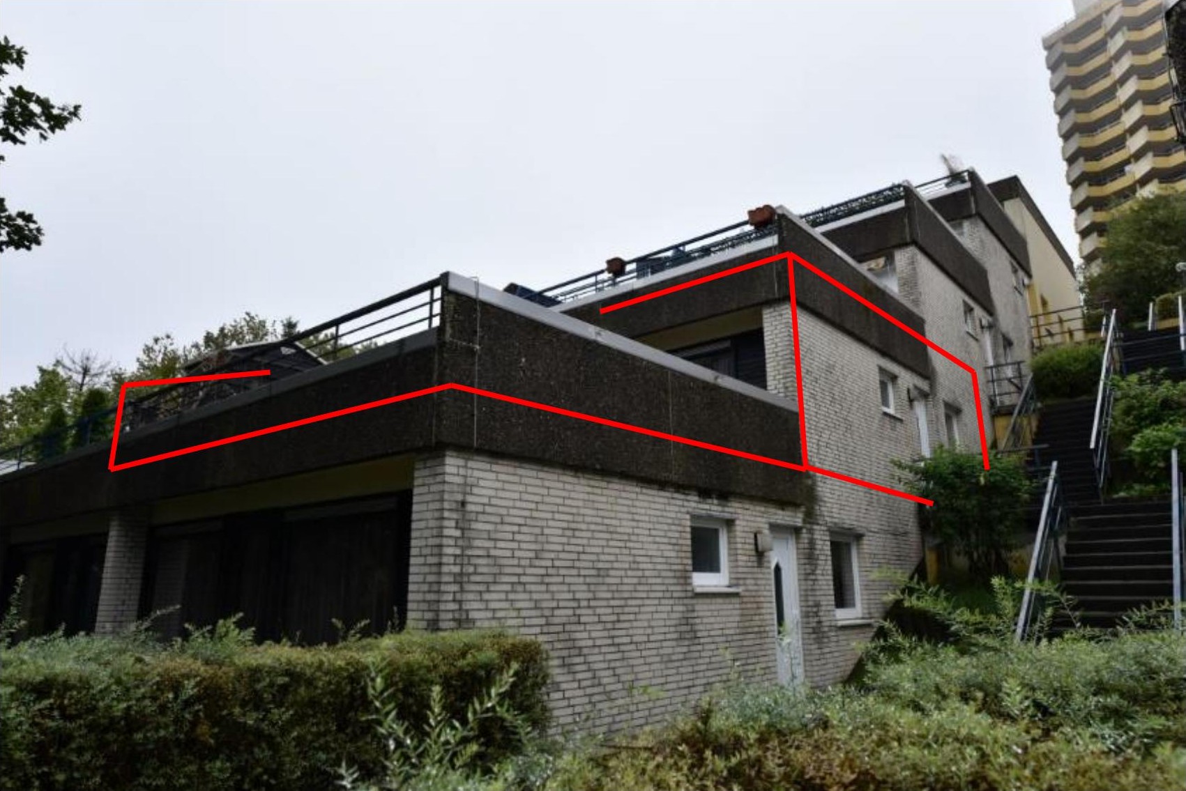 Seitenansicht eines mehrstöckigen Gebäudes mit Ziegelmauerwerk, Fenstern und Dachterrasse mit Geländer in Braunlage