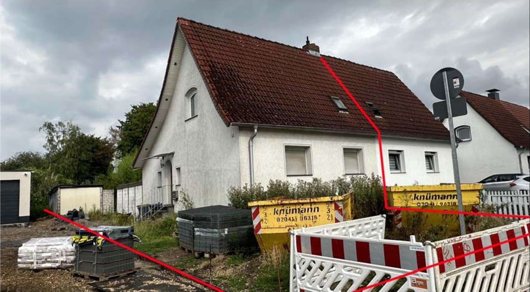 Seitenansicht eines Einfamilienhauses mit rotem Ziegeldach und weißer Fassade, umgeben von Baustellensicherung und Baustoffen in Duisburg, Maxstraße 16