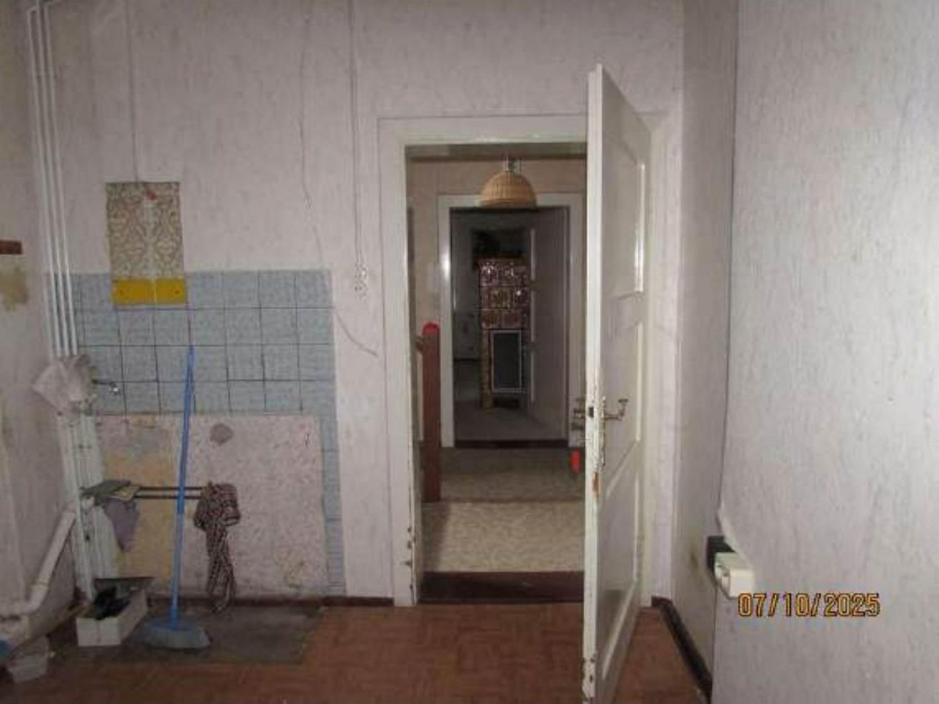 Innenansicht eines Flurs mit offener Tür, Fliesenwand und Reinigungsgeräten im Erdgeschoss eines Zweifamilienhauses in Eilsleben