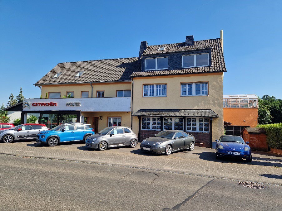 Gebäude mit Citroën-Verkaufsbereich und mehreren geparkten Fahrzeugen vor einer Wohnhausfassade in Wachtberg, Töpferstraße 92. Parkplatzbereich mit verschiedenen Autos