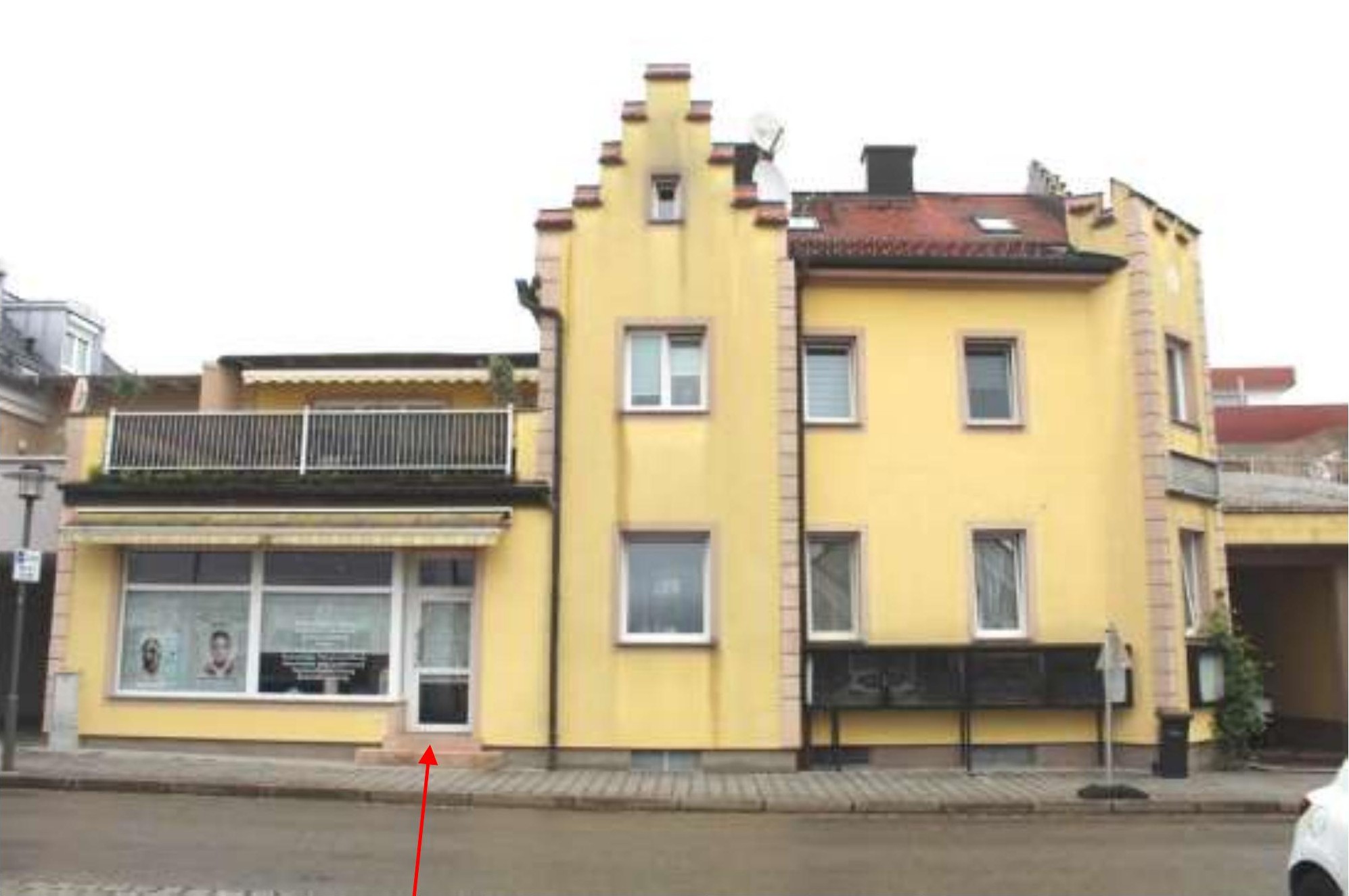 Gelbes Wohn- und Geschäftshaus in Freilassing, Sebastianigasse 2, mit Balkon und Eingang im Erdgeschoss