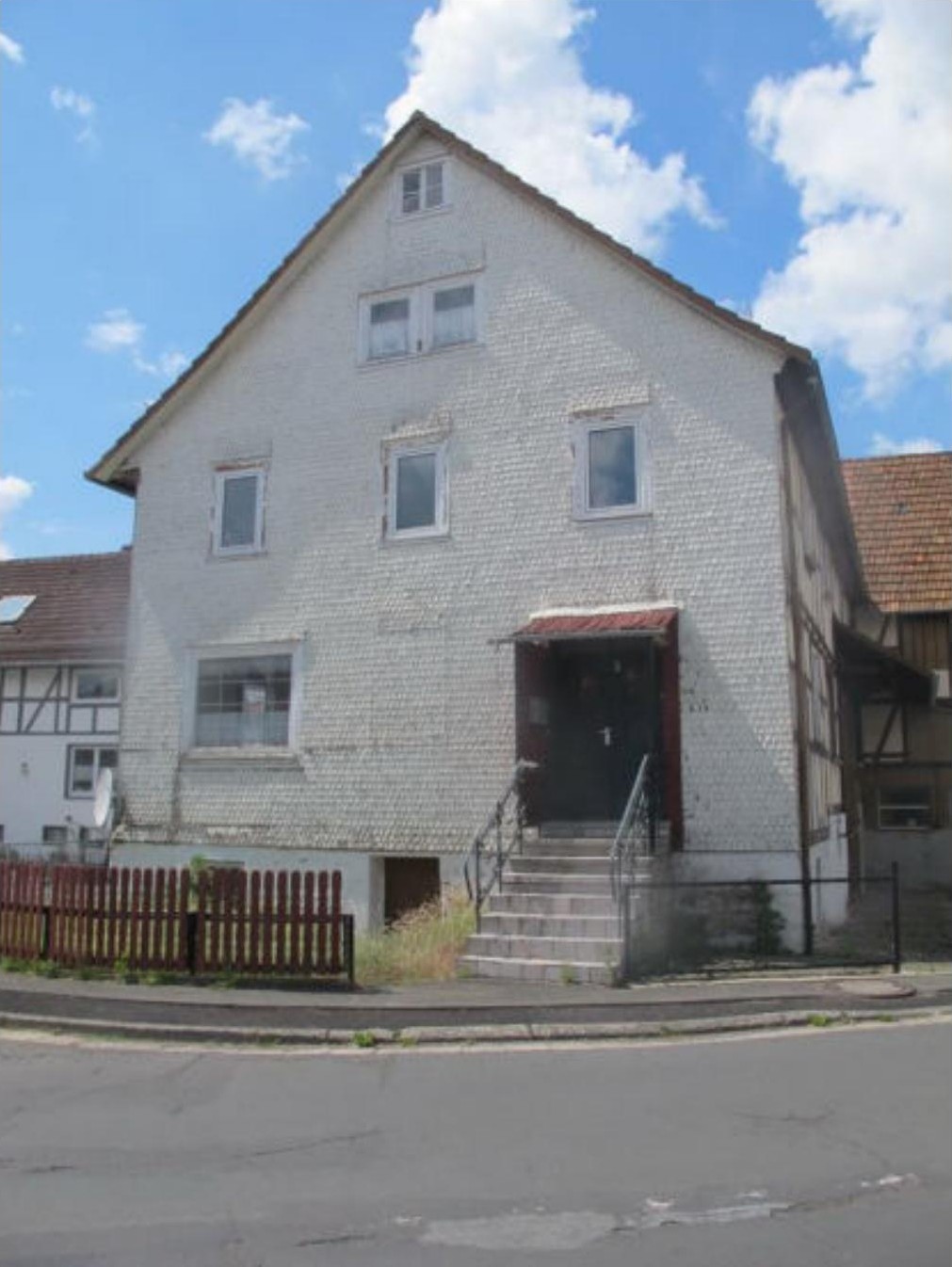 Einfamilienhaus in Oberaula, Bahnhofstraße 3, mit weiß verputzter Fassade, Eingangstreppe und Dachgauben unter blauem Himmel