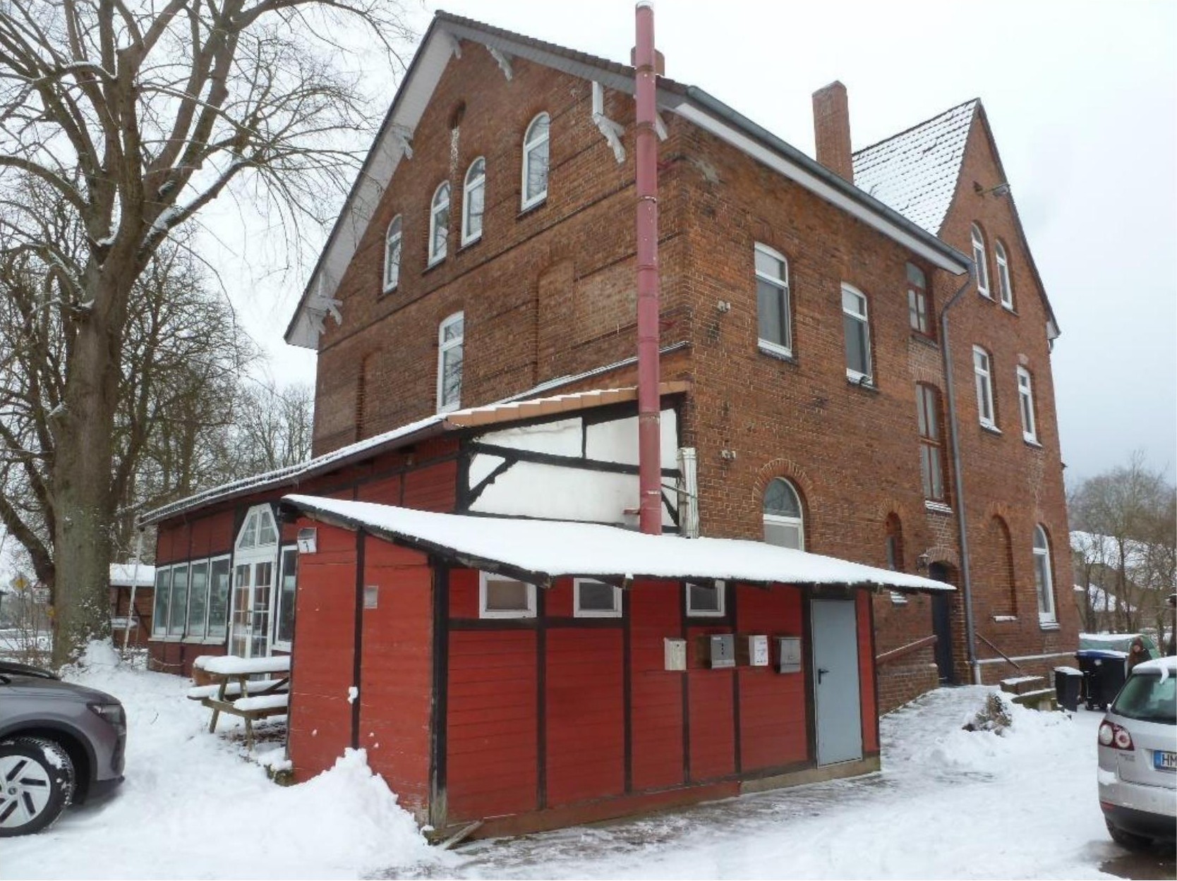 Vorderansicht eines mehrstöckigen Backsteinhauses mit Schneebedeckung, rotem Anbau und Eingangsbereich, Salzhemmendorf, Spiegelberg 7