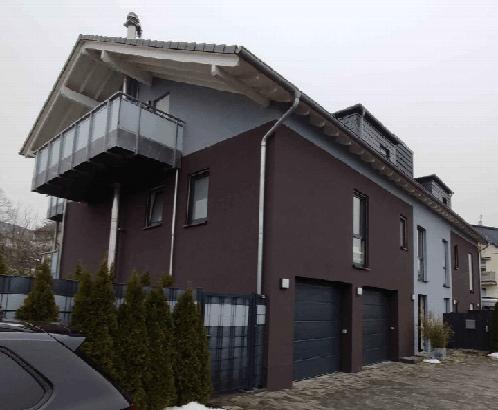 Außenansicht der Garage an der Leipziger Str. 36 in Heiligenhaus, 42579, mit dunkelbrauner Fassade, zwei Garagentoren und einem Balkon im Obergeschoss