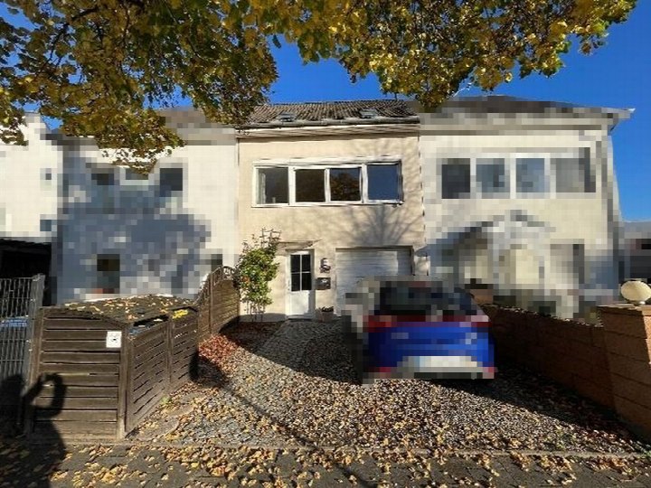 Vorderansicht eines Reihenhauses in Eutin, Sielbecker Landstraße 22, mit Einfahrt, gepflastertem Vorplatz und herbstlichen Blättern unter einem Baum