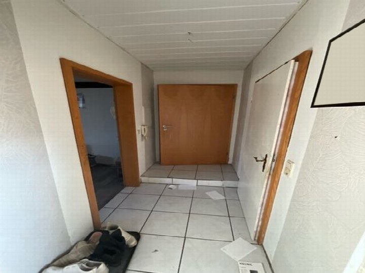 Eingangsbereich eines Mehrfamilienhauses mit Fliesenboden, Holztüren und Schuhen am Boden. Bauernende 34, 39646 Oebisfelde-Weferlingen