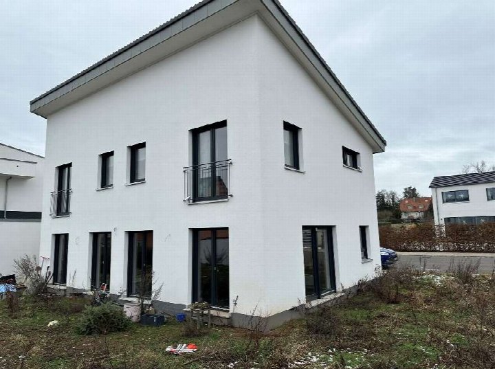 Einfamilienhaus in Cadolzburg, Pfalzhausweg 13, Außenansicht der Seitenfassade mit weißen Wänden, dunklen Fenstern und Balkonen, unberäumter Vorgarten