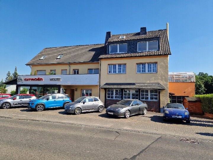 Gebäude mit Citroën-Verkaufsbereich und mehreren geparkten Fahrzeugen vor einer Wohnhausfassade in Wachtberg, Töpferstraße 92. Parkplatzbereich mit verschiedenen Autos