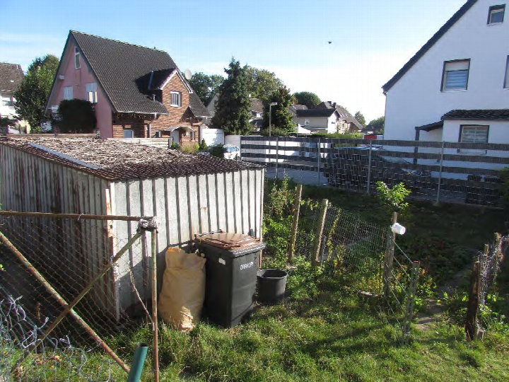 Gartenbereich mit Metallcontainer, Mülltonne, Sack und Zaun, im Hintergrund Wohnhäuser in Bedburg-Blerichen Otten