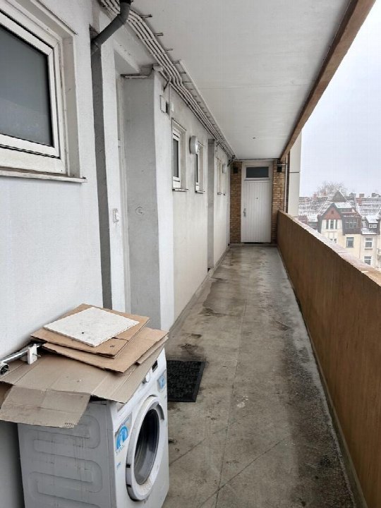 Gedeckter Balkon mit Betonboden, Waschmaschine und Blick auf benachbarte Gebäude in Hannover, Hildesheimer Str. 221