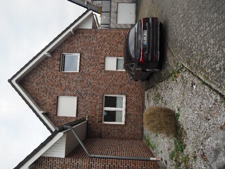 Seitenansicht eines Backsteinhauses mit Fenstern, Dachrinne und geparktem Auto in Gronau, Emmastraße 9