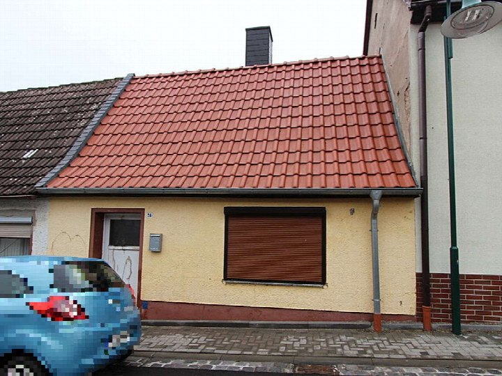 Gelbe Einfamilienhausfassade mit rotem Ziegeldach, Eingangstür und Rollladenfenster an der Neue Straße 24 in Arnstein OT Sandersleben