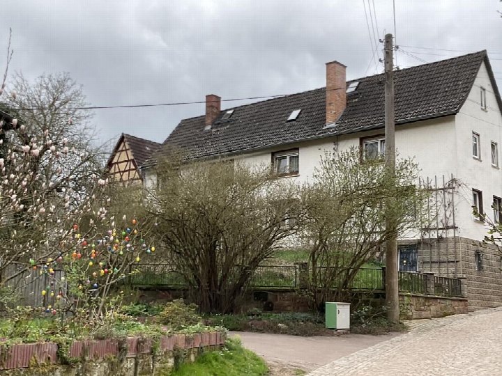 Einfamilienhaus in Bürgel, Ilmsdorf 11, mit weißer Fassade, Satteldach und Vorgarten mit Bäumen und bunten Eiern an einem Baum