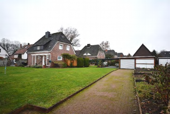 Einfamilienhaus mit Garage und gepflastertem Zugangsweg, umgeben von Rasen und Nachbarhäusern in Bremen-Blumenthal