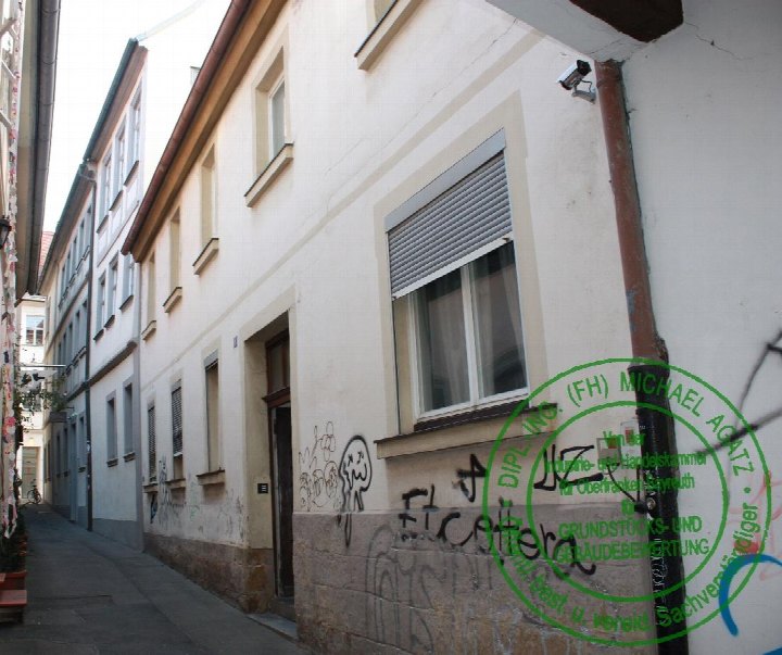 Seitenansicht eines mehrstöckigen Gebäudes in der Hasengasse 1, Bamberg, mit Fenstern, Tür, Steinsockel und Graffiti an der Fassade