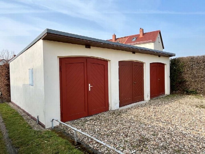 Garage mit drei roten Türen, weißer Fassade und Kiesfläche vor dem Gebäude in Schönebeck, Am Randel