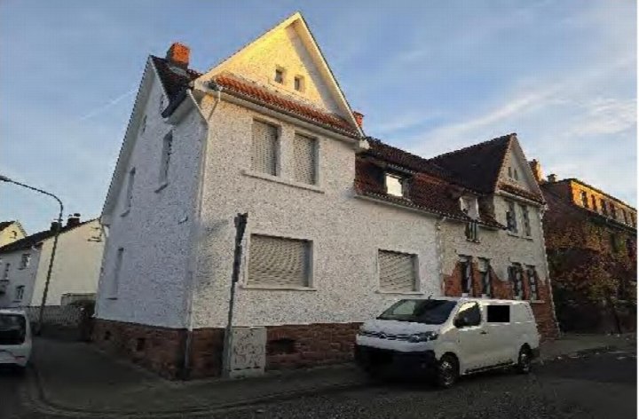 Außenansicht der Doppelhaushälfte Spessartstraße 15 in Hanau, mit weiß verputzter Fassade, rotem Ziegeldach und geparktem Fahrzeug vor dem Haus