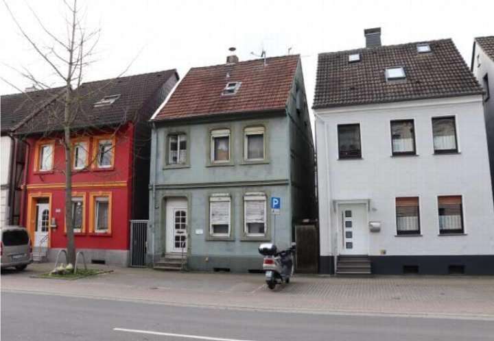 Außenansicht der Wellinghofer Straße 118 in Dortmund mit drei benachbarten Häusern in Rot, Grau und Weiß, geparktem Roller und Baum vorne