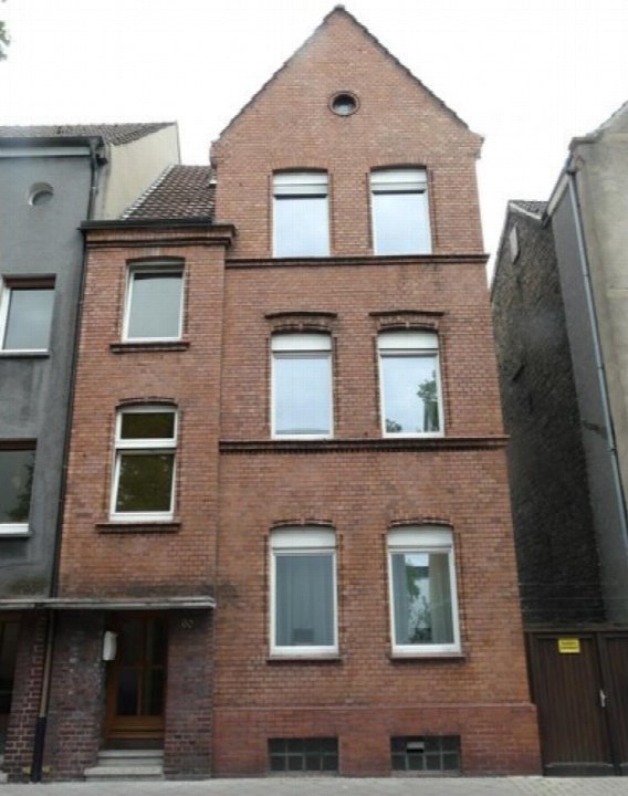 Vorderansicht eines mehrstöckigen Backsteinhauses mit Eingang, Fenstern und Satteldach in Hamm, Schillerstraße 60