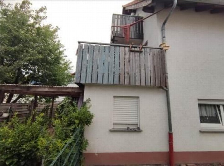 Seitenansicht eines Wohnhauses mit Holzbalkonen, Fenstern und angrenzendem Gartenbereich in Steinau, Brüder-Grimm-Straße 138a