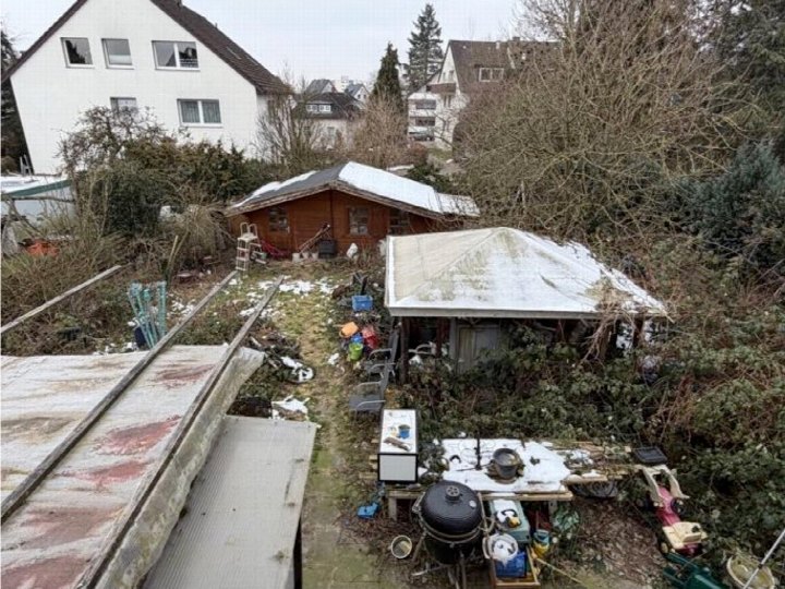 Gartenbereich mit Holzschuppen, überwucherten Pflanzen, Werkzeugen und Schnee. Ansicht von oben, Teil eines Einfamilienhauses in Bad Salzuflen