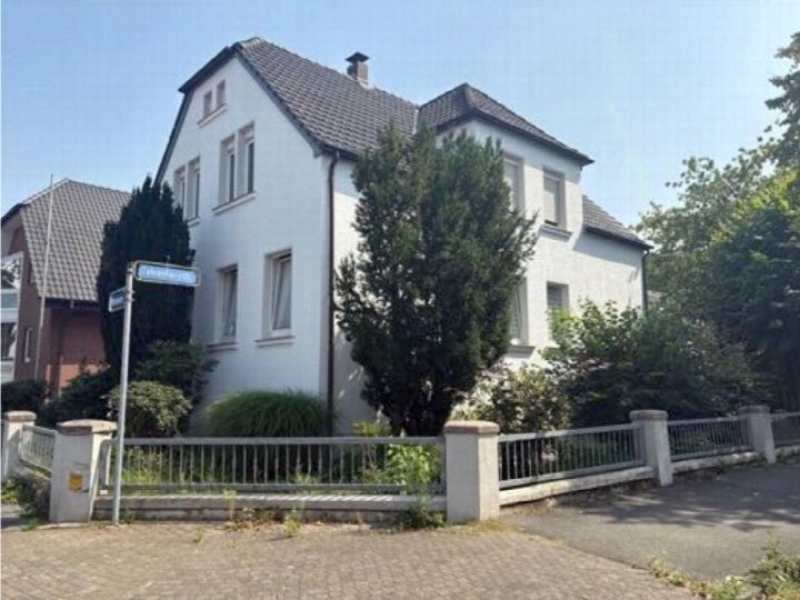 Zweifamilienhaus in Bünde, Wiesenstraße 42, mit weißer Fassade, dunklem Dach und Vorgarten. Straßenname-Schild sichtbar