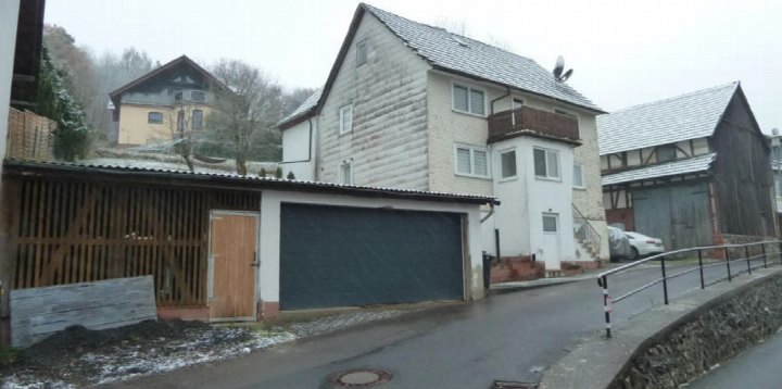 Seitenansicht eines Einfamilienhauses mit Garage, Holzzaun und angrenzenden Gebäuden in Ottrau, Reifenberg 15