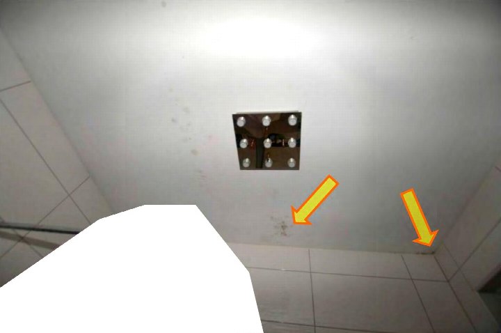 Badezimmerdecke mit quadratischer Leuchte und Fliesenwand, Pfeile markieren Stellen an der Wand