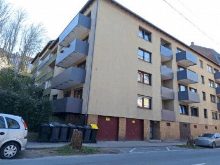Seitenansicht eines mehrstöckigen Wohnhauses mit Balkonen und Garagen im Erdgeschoss, Lärchenweg 44, Langenfeld