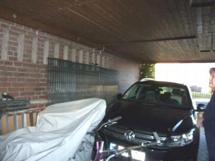 Garage mit schwarzen Volkswagen, abgedecktem Fahrzeug und Backsteinwand mit Metallgitter in Ibbenbüren