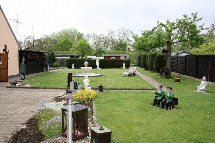 Garten mit Rasenfläche, Weg, Brunnen, Statuen und Gartenmöbeln vor einem zweifamilienhaus in Ratingen