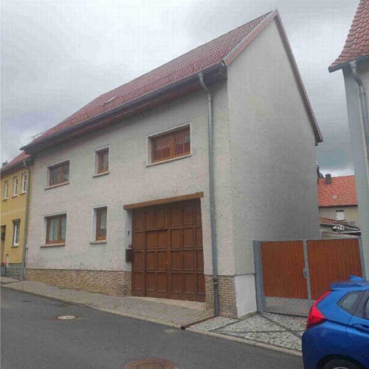Seitenansicht eines Einfamilienhauses mit rotem Ziegeldach, Holzgaragentür und Fenstern in der Burgstraße 7, Weißensee