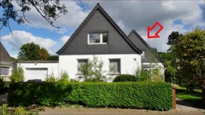 Einfamilienhaus mit weißer Fassade, dunklem Satteldach und Vorgartenhecke, Ansicht von vorne