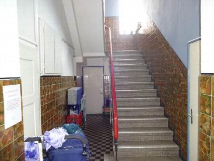 Treppenhaus mit grauen Stufen, rotem Geländer und braunen Fliesenwänden in einem Mehrfamilienhaus in Bochum