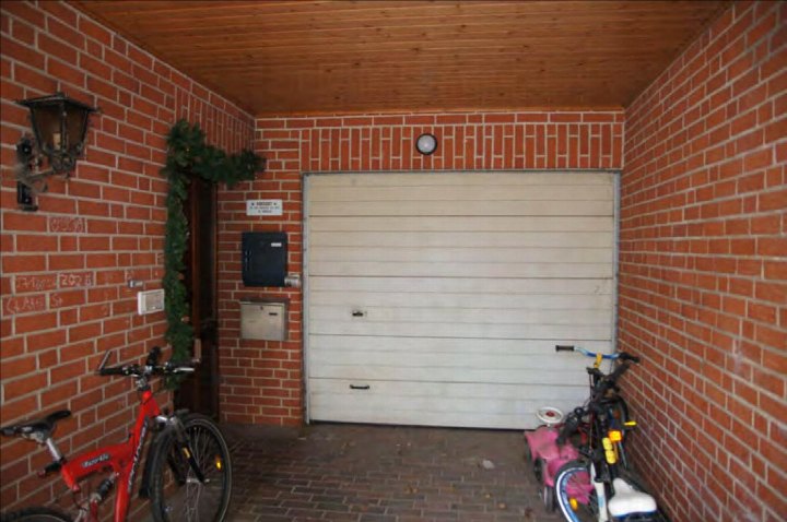 Garage mit roten Ziegelwänden, Holzdecke, Rolltor und zwei Fahrrädern im Inneren