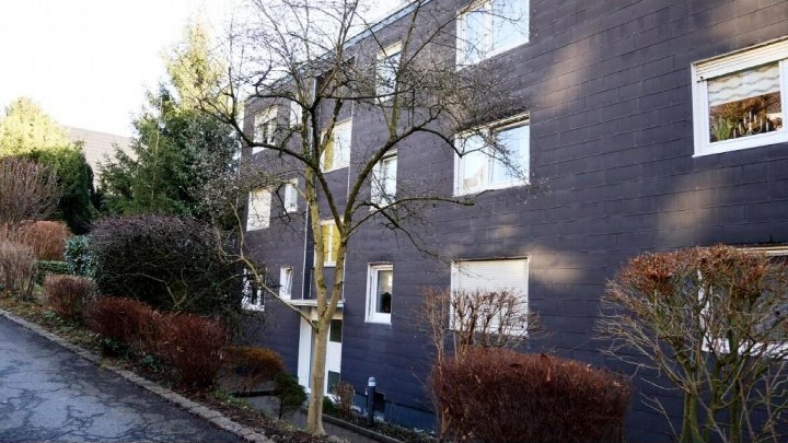 Seitenansicht eines Mehrfamilienhauses mit dunkler Fassade, Fenstern und Beeteinfassung in Gevelsberg, Südstraße