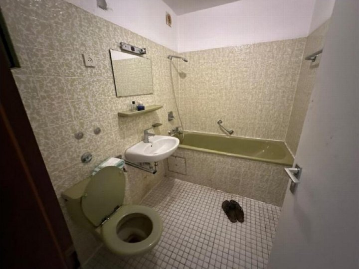 Badezimmer mit WC, Waschbecken, Badewanne und Fliesenwand. Bodenfliesen, Spiegel und Dusche sichtbar