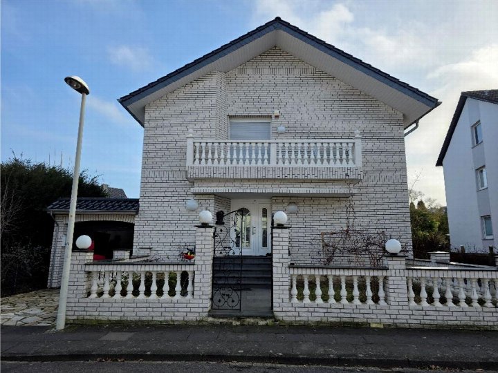 Vorderansicht eines Einfamilienhauses mit weiß verputzter Fassade, Balkon und Eingangstür, Standort Bonn, Maarweg 34