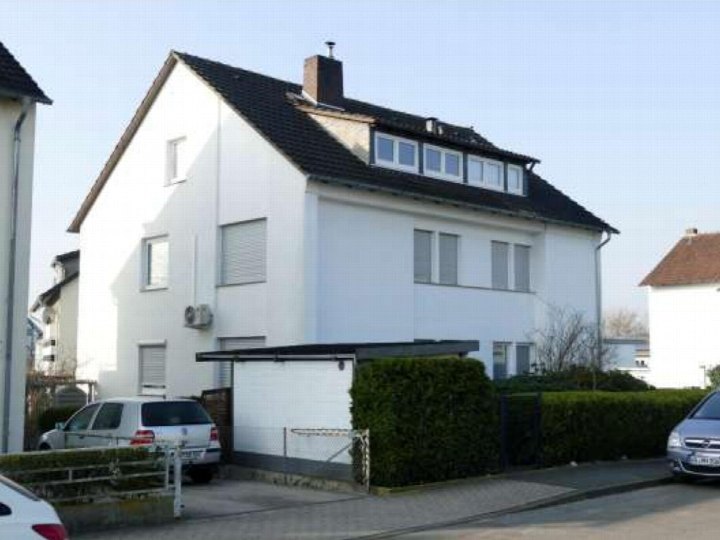 Seitenansicht eines weißen Mehrfamilienhauses mit dunklem Dach, Fenstern, Garage und Hecke in Lemgo, Am Lindenhaus 2