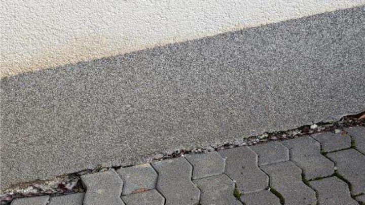 Nahaufnahme der Außenfläche mit sechseckigen Pflastersteinen und Betonrand neben einer Wand der Eigentumswohnung in Wirges