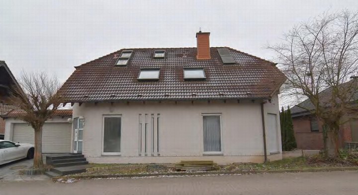 Einfamilienhaus mit Satteldach, Dachfenstern und Eingangsbereich, Garagenanbau links, kahle Bäume im Vorgarten, Ansicht von vorne