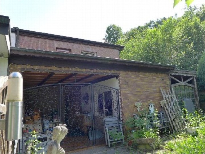 Gartenbereich mit Pflanzen, Statue und überdachter Terrasse an einem Backsteinbau in Dortmund, Orchideenweg 32