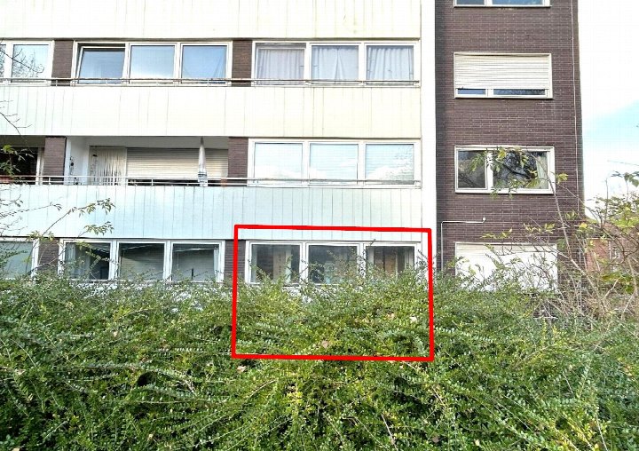 Außenansicht eines Mehrfamilienhauses mit Fenstern und Balkonen, teilweise verdeckt durch Büsche, in Münster, Merschkamp 49