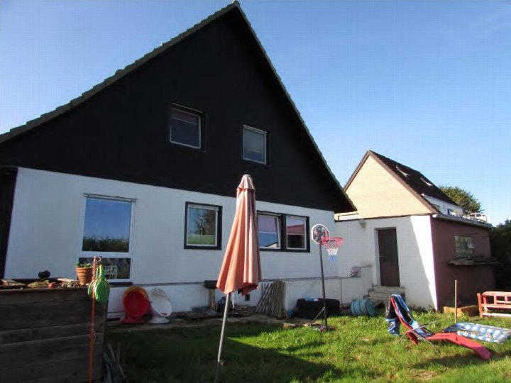 Hinterhof eines Einfamilienhauses mit Rasen, Sonnenschirm, Liegestuhl und Basketballkorb