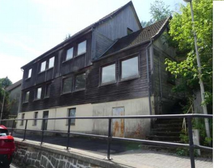 Seitenansicht eines Mehrfamilienhauses mit dunkler Holzfassade, mehreren Fenstern und Betonsockel in Clausthal-Zellerfeld, Bergstr. 19